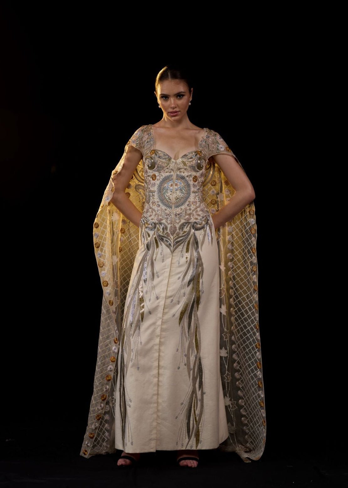https://cdn.shopify.com/s/files/1/0088/3441/6706/files/a-sheer-neck-floor-length-embroidered-gown-cape-drapes-from-the-shoulders-6823494.jpg?v=1752388529