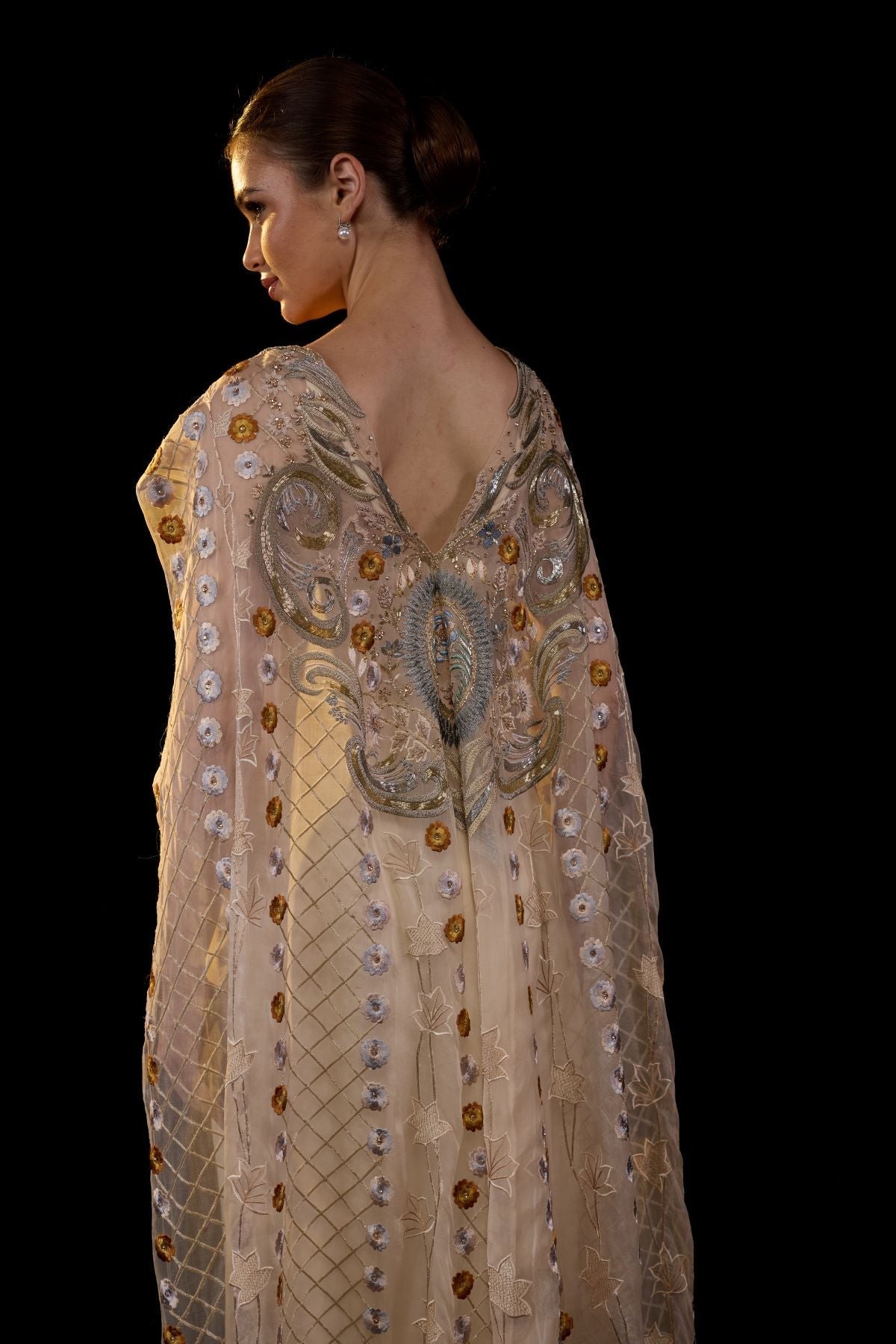 https://cdn.shopify.com/s/files/1/0088/3441/6706/files/a-sheer-neck-floor-length-embroidered-gown-cape-drapes-from-the-shoulders-4139502.jpg?v=1752388531