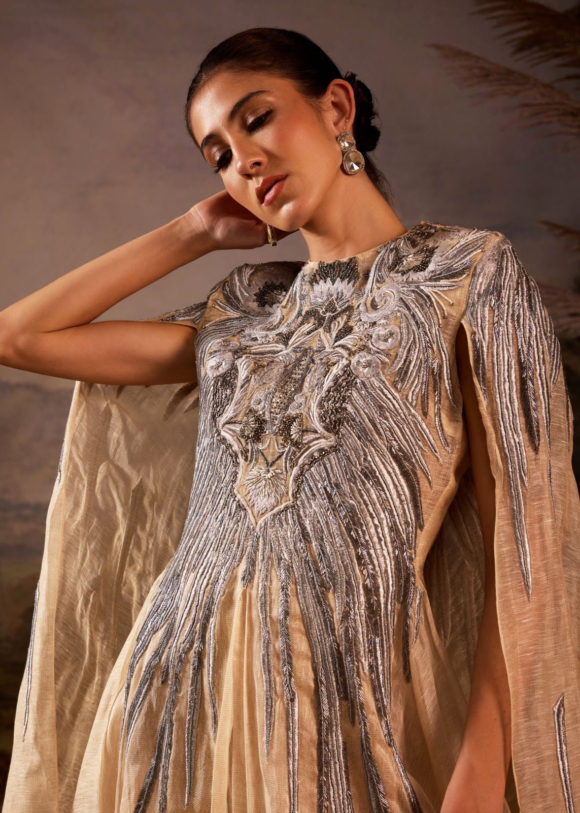 https://cdn.shopify.com/s/files/1/0088/3441/6706/files/champagne-draped-cape-gown-with-ornate-silver-embroidery-2297999.jpg?v=1753781125
